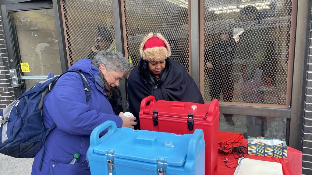 Photo of Kim Wright offering community members coffee and hot chocolate.
